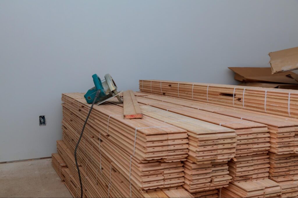 Several stacks of plain wood inside a home, ready to use for flooring.