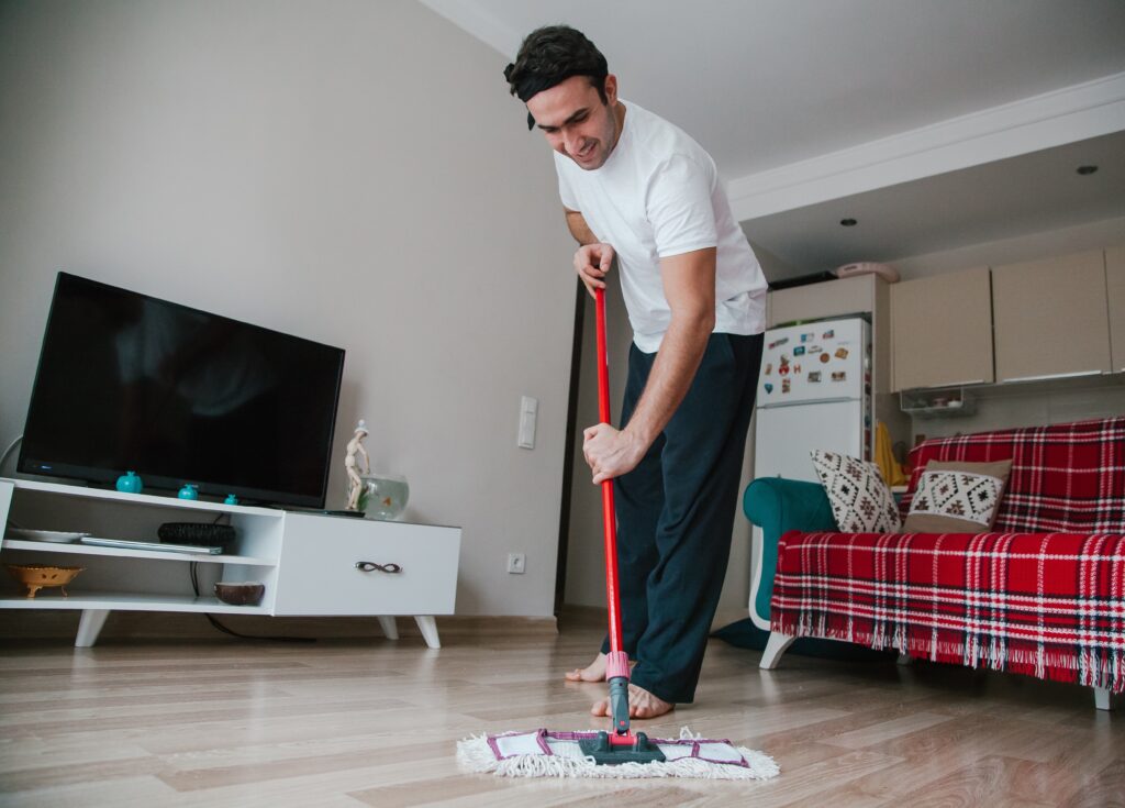 A young man cleans wood floors at home
