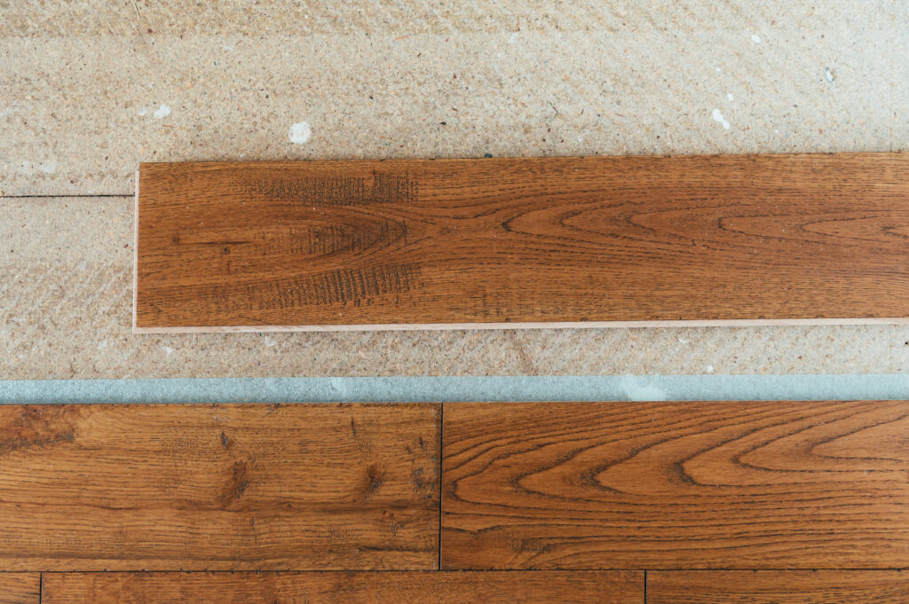 A selection of hardwood floor planks fanned out on top of carpet flooring.
