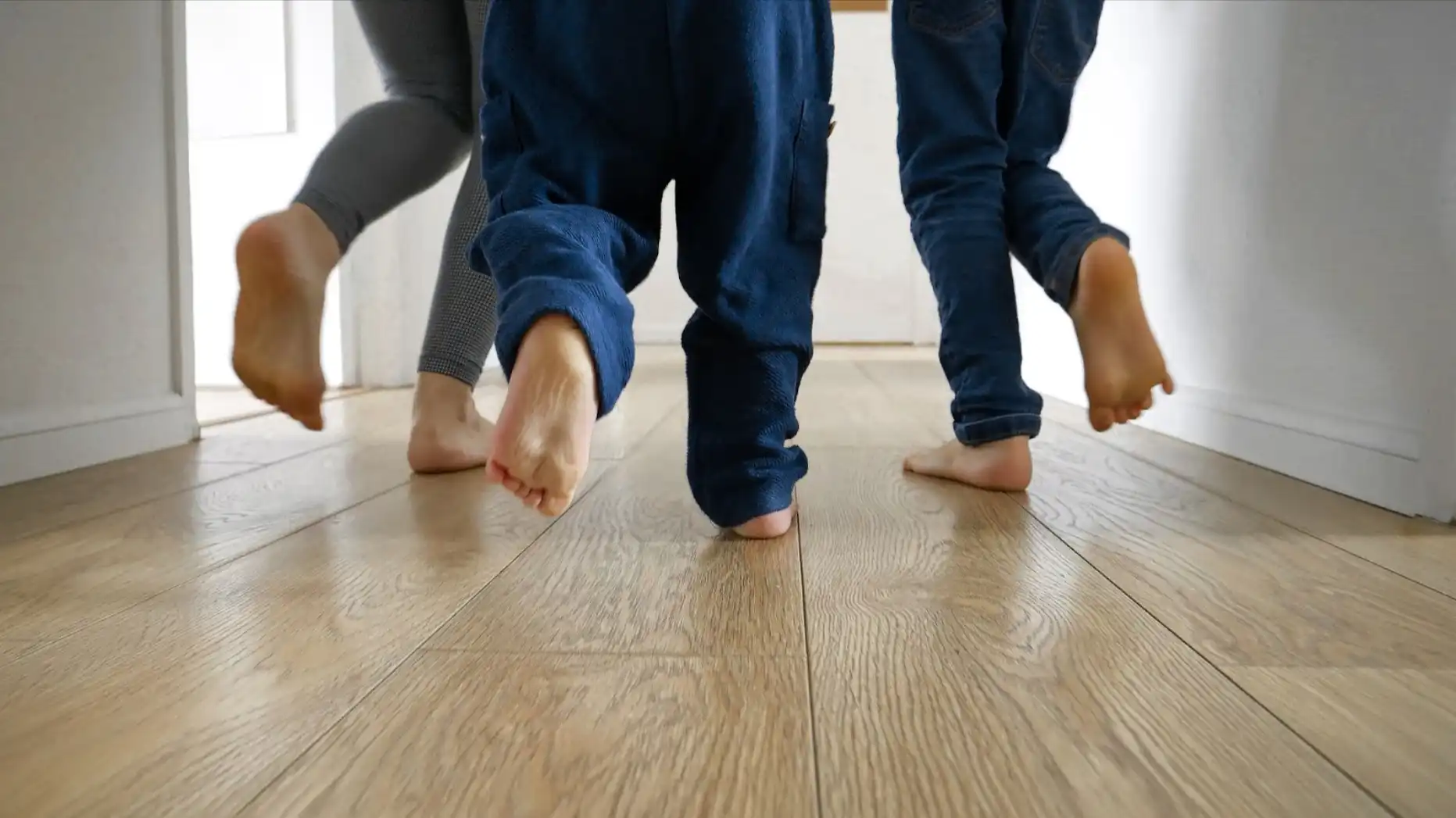 A family walking barefoot on hardwood flooring.