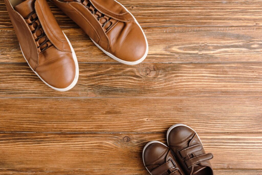 Two pairs of shoes on wood flooring. 