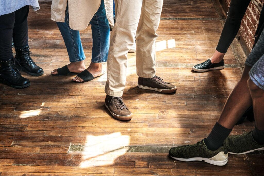 A group of people standing on a hardwood floor.